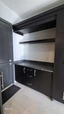 Mud room from garage, light tile patterned flooring, dark cabinets, dark stone counters, and a textured ceiling