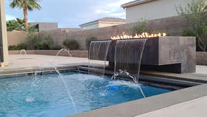 View of swimming pool with a fenced backyard and a patio area with water features