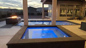 Outdoor pool with a patio area, an in-ground hot tub, an outdoor fire pit, and a fenced backyard