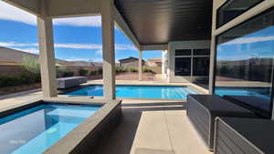 View of swimming pool featuring an in-ground hot tub, a patio area, and a fenced backyard