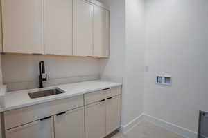 Washroom featuring hookup for a washing machine and cabinet space