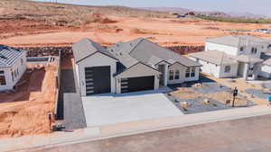 View of front of property featuring an attached garage, stone siding, driveway, a mountain view, and view of desert landscape