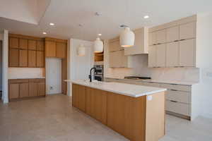 Kitchen featuring decorative light fixtures, wall chimney exhaust hood, decorative backsplash, a spacious island, and cream cabinets