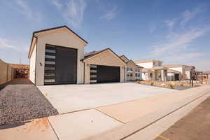 View of front of property with a garage, concrete driveway, a residential view, and stucco siding