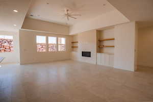 Unfurnished living room with built in shelves, a glass covered fireplace, recessed lighting, ceiling fan, and light flooring