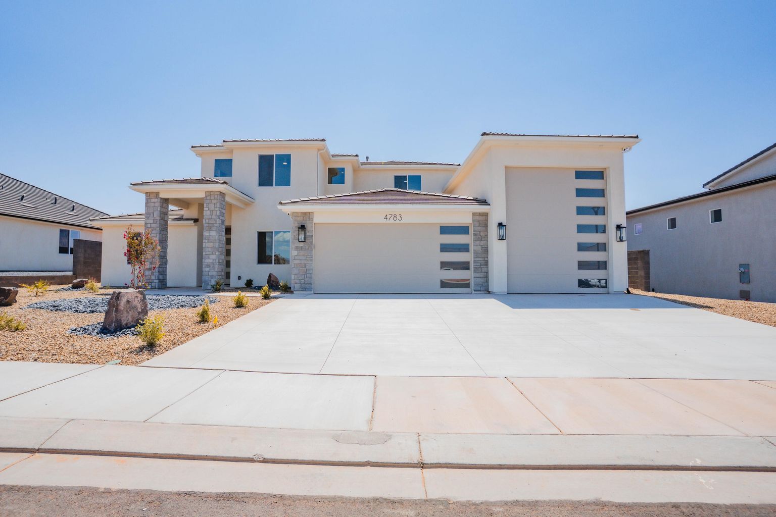 View of front of home featuring stone siding, a tiled roof, a garage, and stucco siding