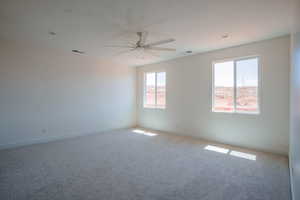 Carpeted spare room with a ceiling fan and baseboards