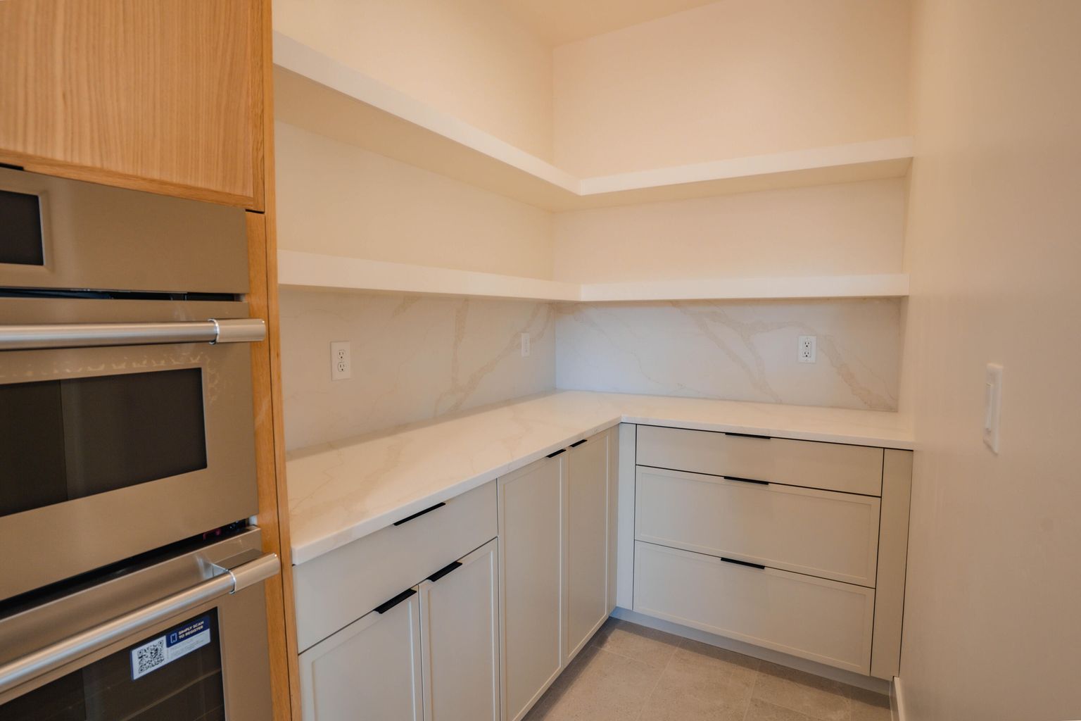 Kitchen with stainless steel double oven, light stone counters, and light tile patterned floors
