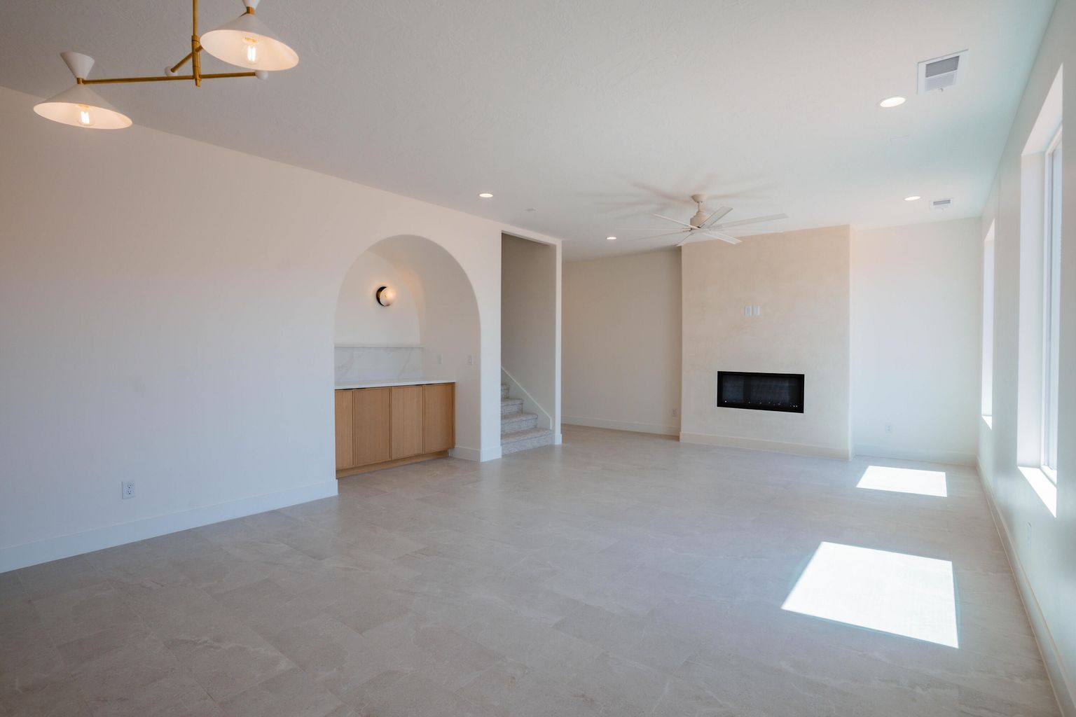 Unfurnished living room with a glass covered fireplace, ceiling fan, recessed lighting, and stairs