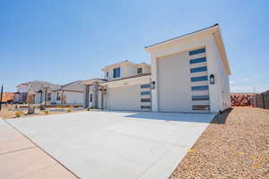 Contemporary house with concrete driveway, an attached garage, stucco siding, and stone siding