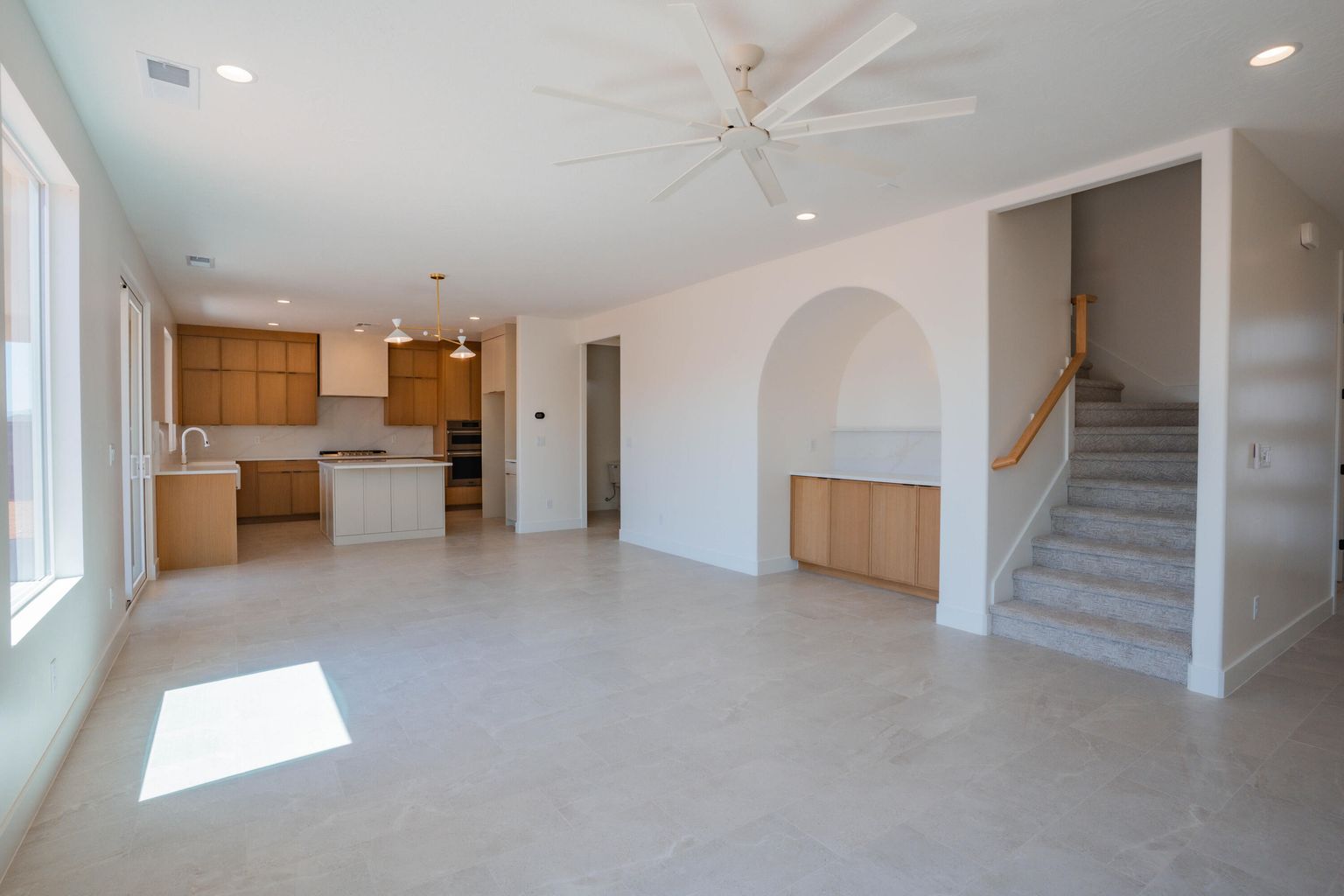 Unfurnished living room featuring recessed lighting, stairway, ceiling fan, and a chandelier
