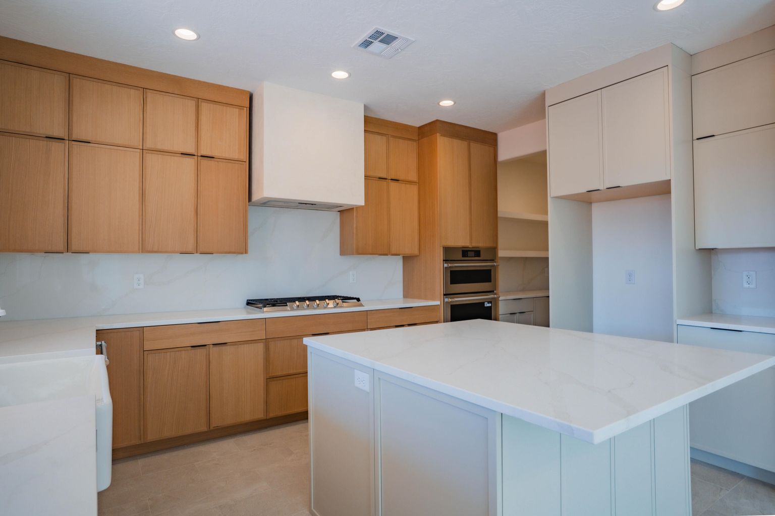 Kitchen with light stone counters, a center island, recessed lighting, wall chimney range hood, and modern cabinets
