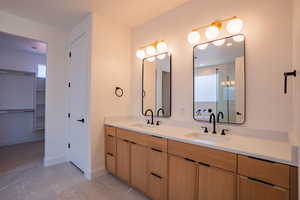 Full bath with a walk in closet, double vanity, and a shower stall