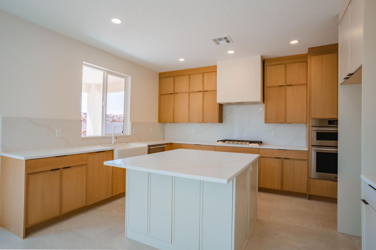 Kitchen with light brown cabinets, recessed lighting, modern cabinets, appliances with stainless steel finishes, and custom exhaust hood
