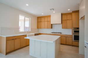 Kitchen with light brown cabinets, recessed lighting, modern cabinets, appliances with stainless steel finishes, and custom exhaust hood