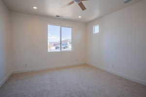 Spare room featuring light colored carpet, ceiling fan, and recessed lighting