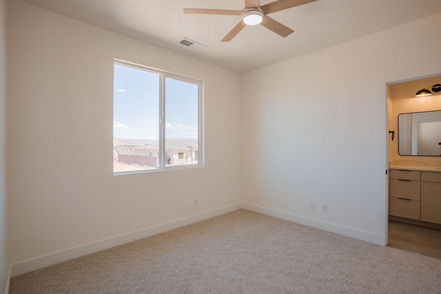Unfurnished bedroom with light carpet, ceiling fan, and ensuite bath