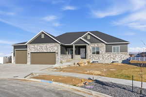 Custom spec house with covered porch, a garage, concrete driveway, and stone siding