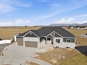 View of front facade with stone siding, an attached garage, RV driveway and outside shed.