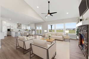 Living room with a fireplace, light wood finished floors, vaulted ceiling, a ceiling fan, and recessed lighting