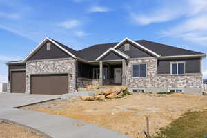 Craftsman-style house featuring covered porch, a garage, stone siding, and driveway