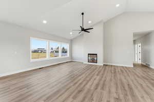 Unfurnished living room featuring light wood finished floors, high vaulted ceiling, recessed lighting, and a ceiling fan
