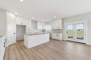 Kitchen featuring a kitchen island, light wood-type flooring, white cabinets, and recessed lighting