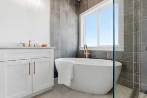 Full bath featuring double vanity, a walk in closet, and light marble finish flooring