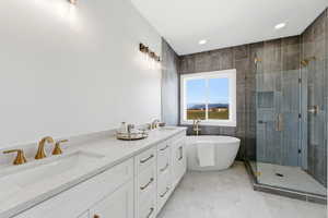 Full bathroom featuring a shower stall, double vanity, a freestanding bath, recessed lighting, and tile walls