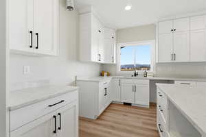 Kitchen featuring light wood-type flooring, white cabinetry, light stone countertops, and recessed lighting