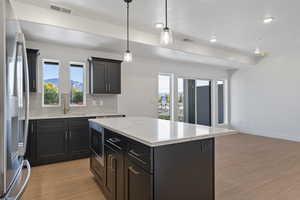 Kitchen featuring decorative backsplash, stainless steel fridge, light wood-type flooring, pendant lighting, and recessed lighting