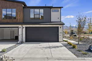 Contemporary house featuring stone siding, concrete driveway, a mountain view, and a garage