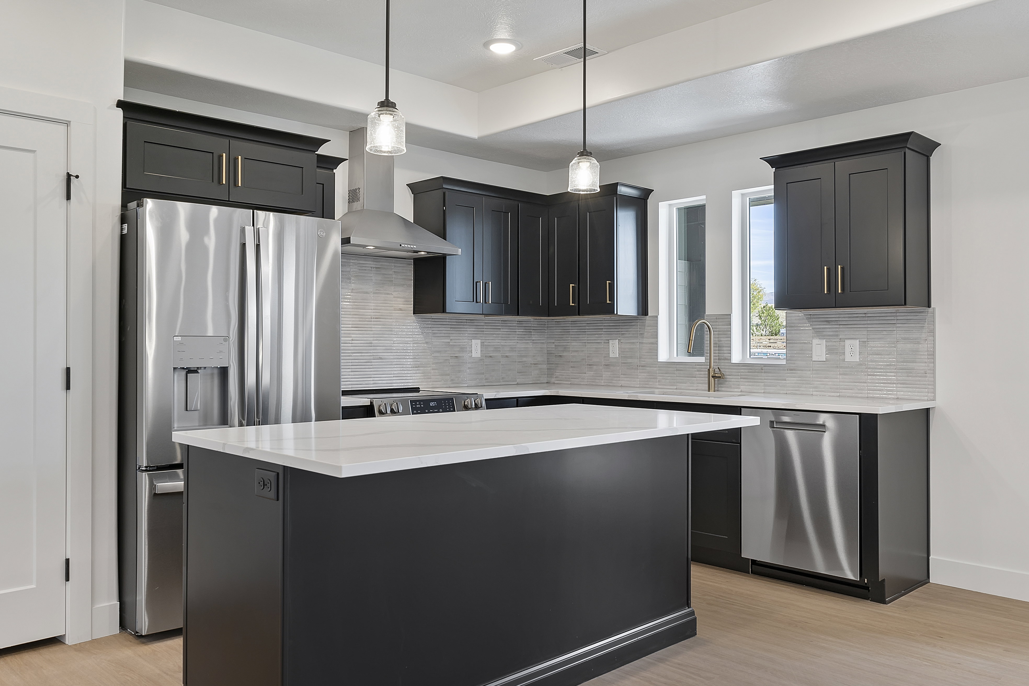 Kitchen with hanging light fixtures, stainless steel appliances, wall chimney range hood, tasteful backsplash, and recessed lighting