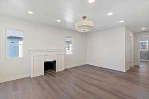 Unfurnished living room featuring plenty of natural light, a fireplace, recessed lighting, and wood finished floors