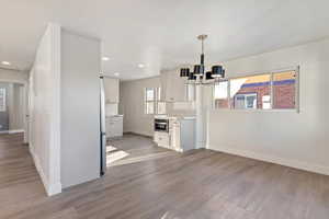 Unfurnished dining area featuring light wood-style flooring, a chandelier, and recessed lighting