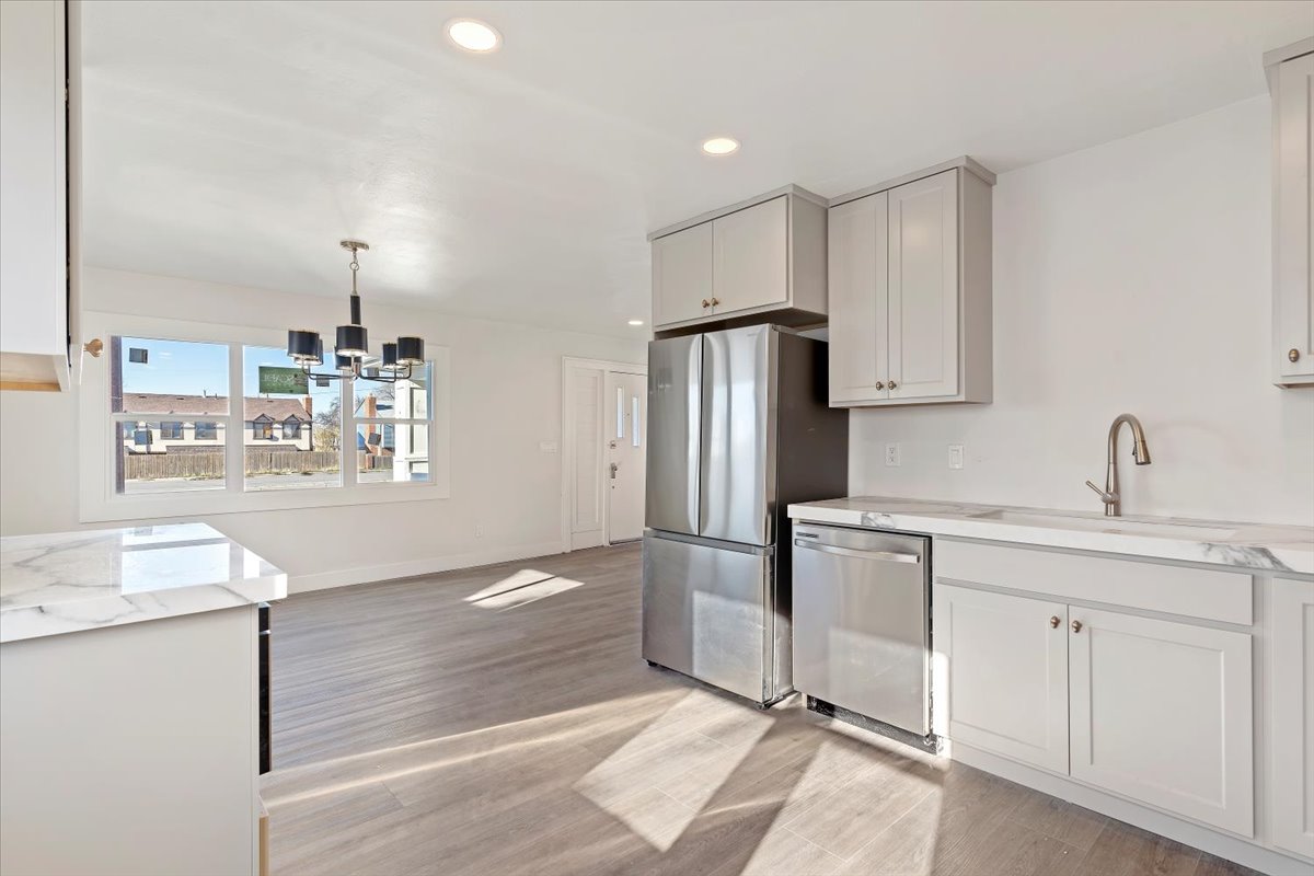 Kitchen featuring decorative light fixtures, stainless steel appliances, recessed lighting, light stone countertops, and light wood-style flooring