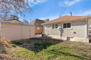 Back of house featuring brick siding, a patio, and a yard