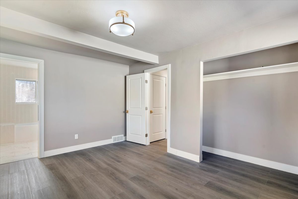 Unfurnished bedroom with dark wood-style floors, a closet, and ensuite bathroom