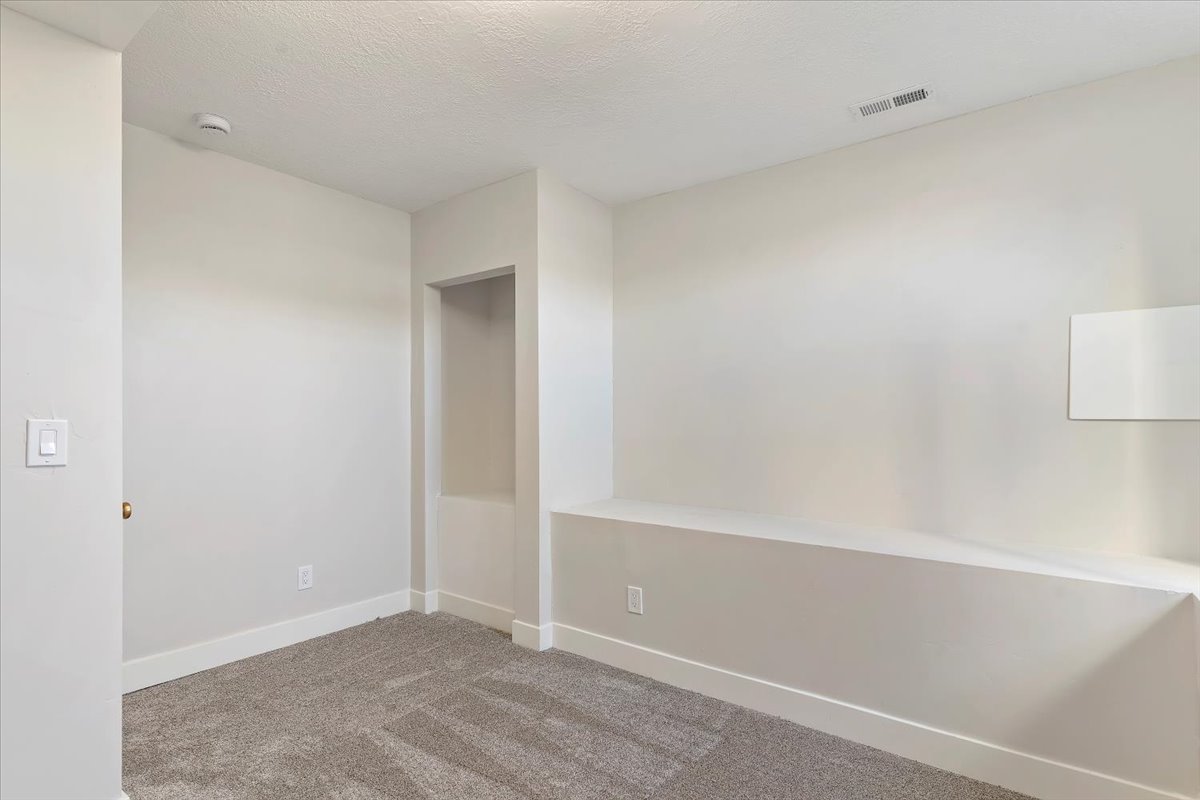 Carpeted spare room with baseboards and a textured ceiling