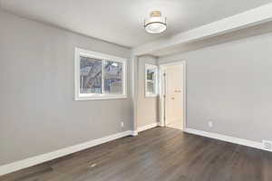 Empty room with baseboards and dark wood finished floors