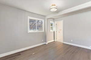 Unfurnished room with baseboards and dark wood-style flooring