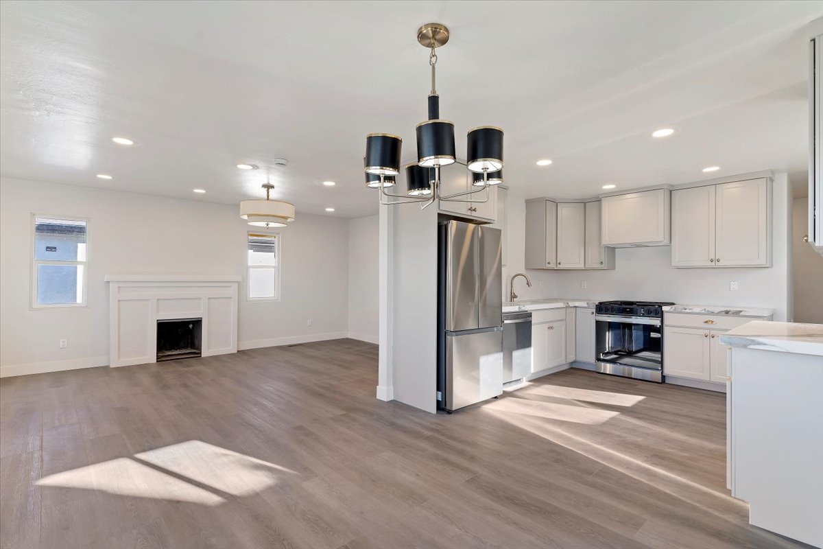 Kitchen with stainless steel appliances, light wood-style flooring, a chandelier, open floor plan, and recessed lighting
