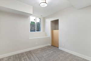 Carpeted spare room featuring baseboards