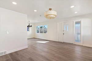 Entrance foyer with wood finished floors, recessed lighting, and a chandelier