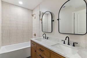 Bathroom featuring shower / tub combination, double vanity, and recessed lighting
