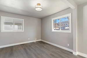 Empty room with baseboards and dark wood-style flooring