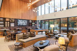 Living area featuring billiards table, wooden walls, a high ceiling, and an accent wall