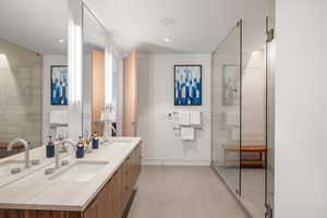 Full bath with double vanity, recessed lighting, and a shower with door