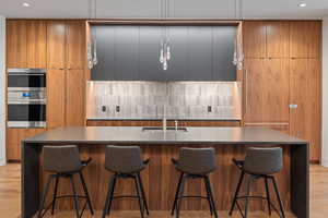 Kitchen with brown cabinetry, modern cabinets, a large island, a kitchen breakfast bar, and recessed lighting