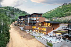 Rear view of property with a patio, a balcony, a mountain view, driveway, and a wooded view